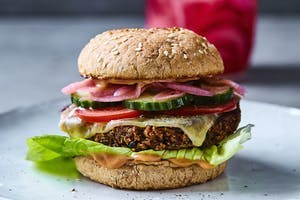Vegeburgeri mustapapupihvillä Vegeburgeri, jossa salaattia, kurkkua, tomaattia, punasipulia ja juustoa